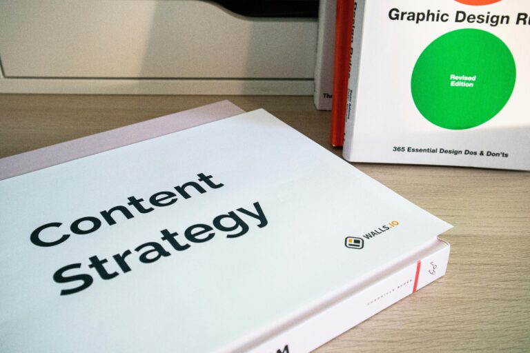 Books on content strategy and graphic design essentials resting on a wooden desk.