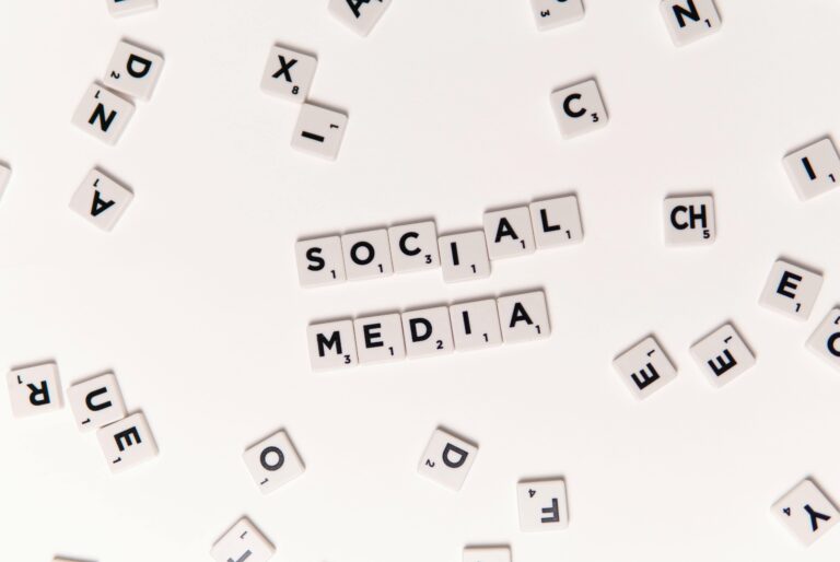 Flat lay of letter tiles spelling Social Media with scattered white tiles on a surface.